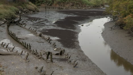 Cave-of-a-wooden-boat,-at-the-bottom-of-a-river-at-low-tide