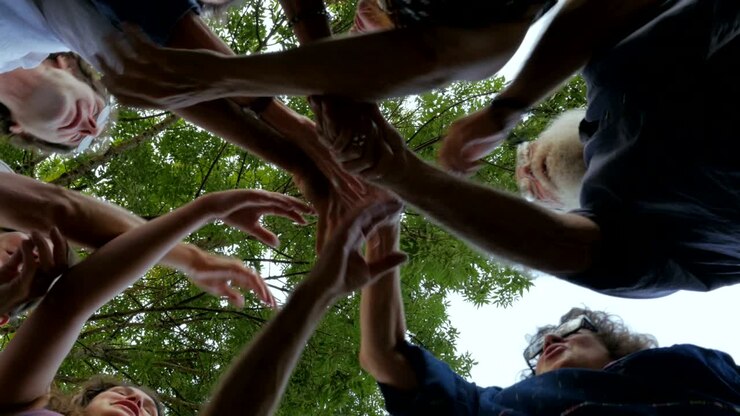 Um grande grupo de pessoas em círculo apertando as mãos