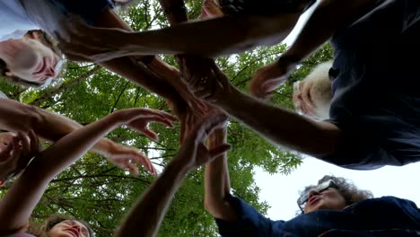 un gran grupo de personas de pie en un círculo y darse la mano