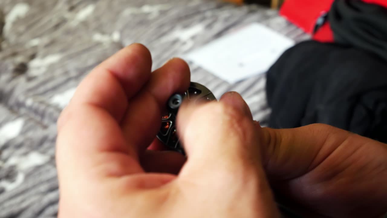 Male hands tighten hobby fpv drone motor onto carbon fibre frame testing strength close up shot