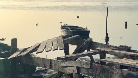 a cinematic and tranquil setting featuring an aged and weathered wooden structure by the water's edge, with two fishing boats peacefully afloat in the water