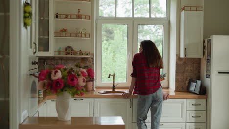 woman standing in a kitchen looking out the window