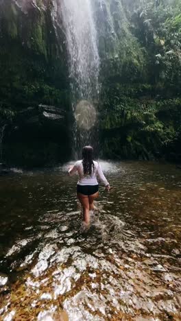 woman enjoying a waterfall in a tropical rainforest