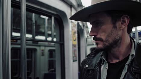 rugged cowboy in leather jacket and western hat sitting contemplatively inside subway train, embodying urban rural cultural contrast during daily commute through city transportation system