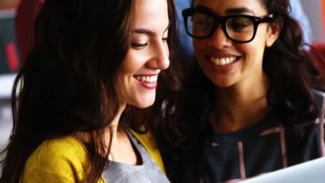 Smiling-female-executives-discussing-over-laptop-during-meeting