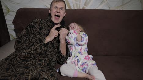 small daughter with her father watching interesting film with great emotions