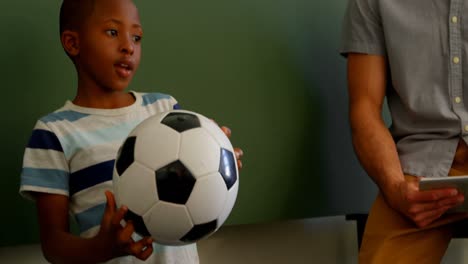 african american schoolboy standing with football in classroom at school 4k