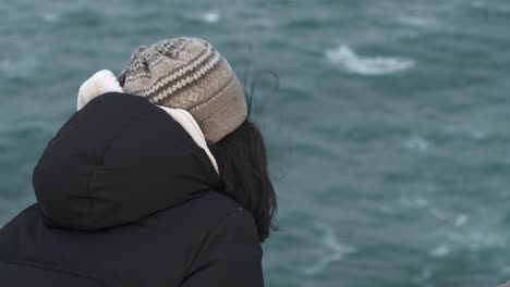 Mujer-Con-Ropa-De-Invierno-Frente-Al-Océano-En-Un-Acantilado-Ventoso