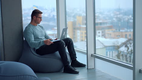 man working on laptop in modern office with city view