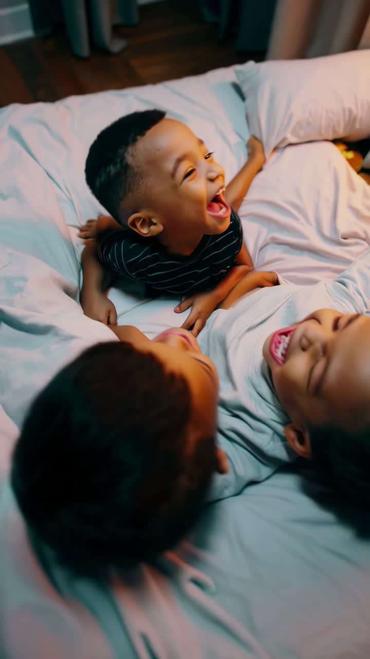 Three joyful boys laughing and playing together in bed