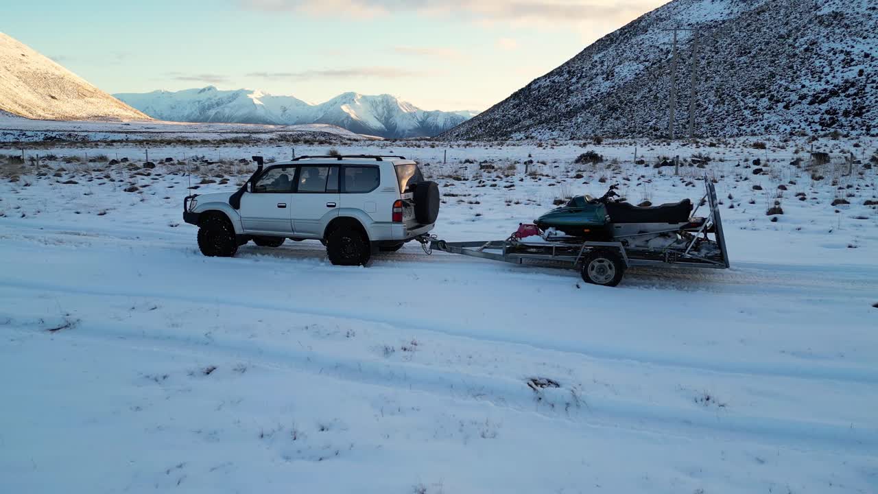 Truck tows a trailer with Ski-Doo in fresh snow, New Zealand.