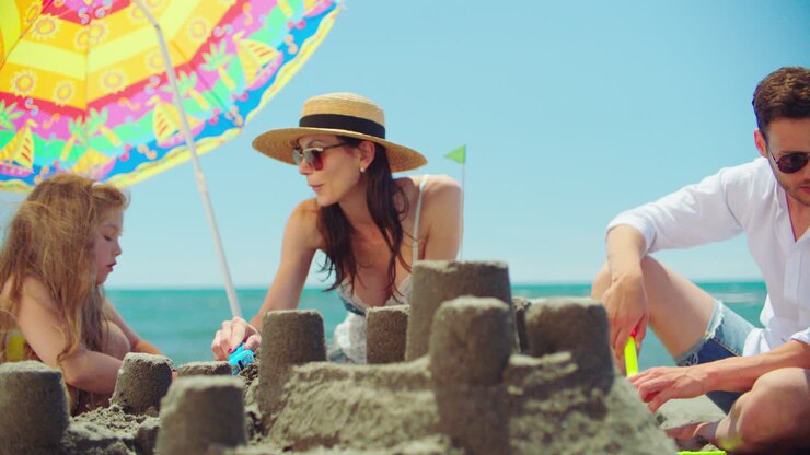 Una famiglia costruisce un castello di sabbia sulla spiaggia