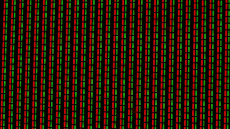 Working pixels in the screen color TV, with a video playback close up. Green and red pixels flicker against a black background. Macro