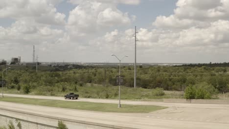 a black truck passes through on road by a manufacturing plant