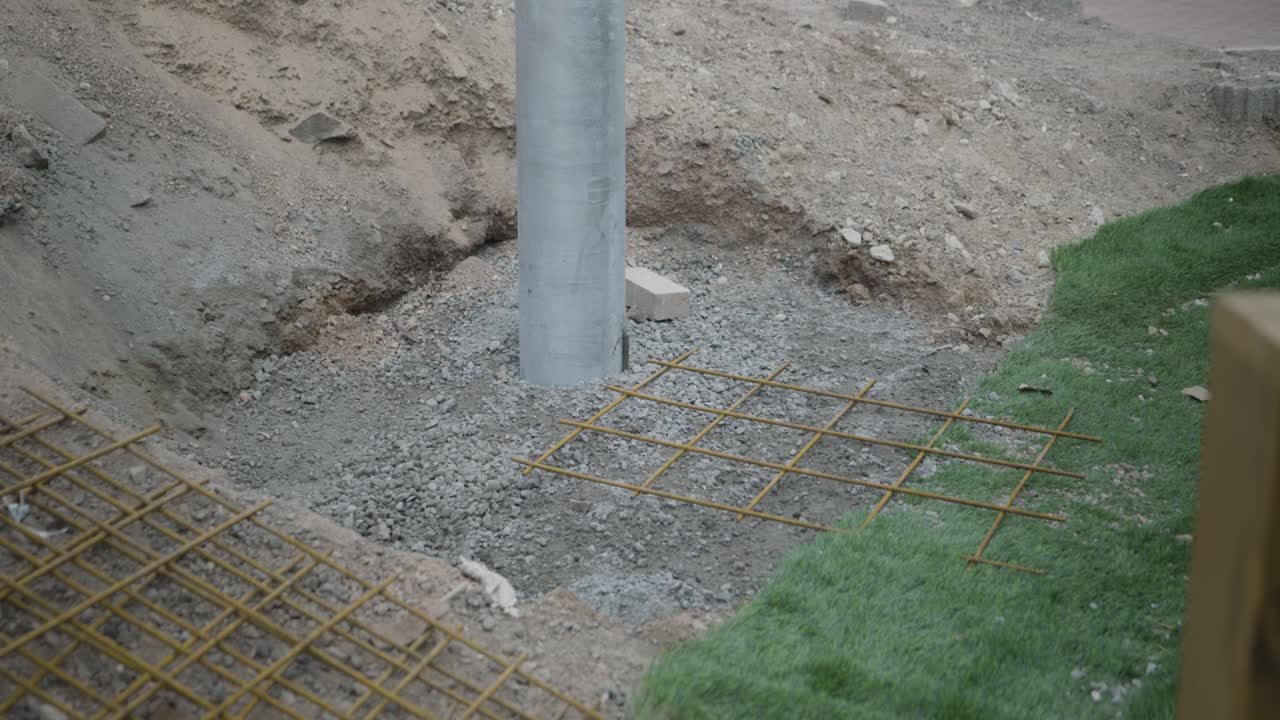 Steel reinforcing shees lay beside a newly installed post in outdoor area