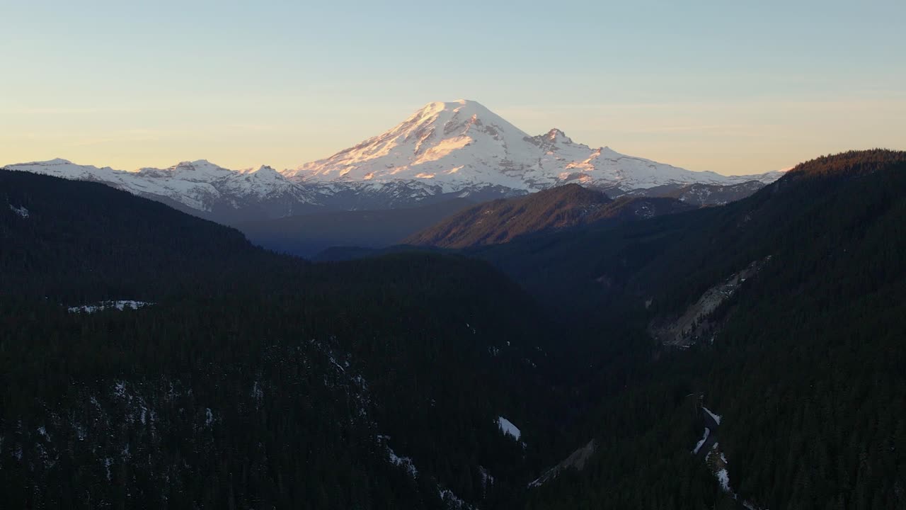 Mount Rainier at sunset, with golden light, aerial pull back