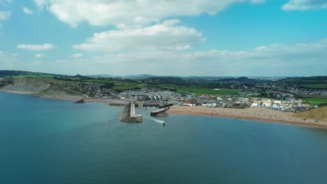 Boat-on-Water-Leaving-Bridport-Harbour-off-coast-of-Dorset,-England,-Aerial