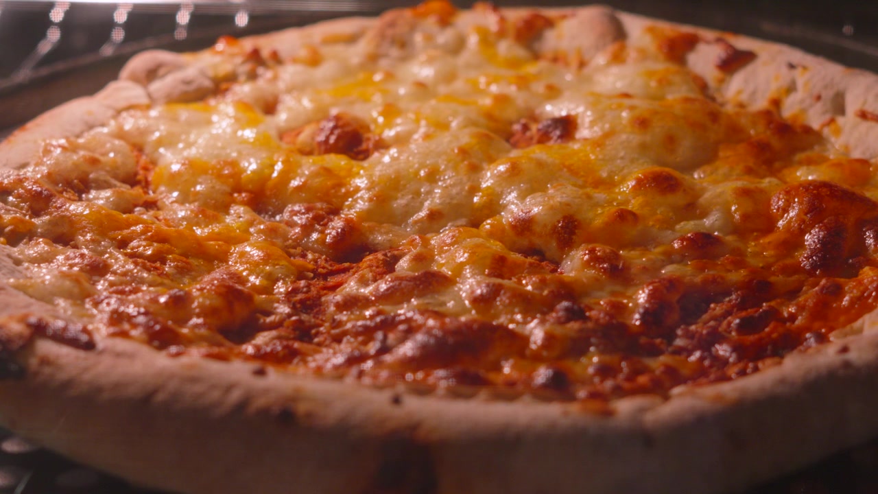 Lenta transizione di messa a fuoco su classica pizza Margherita con bordo ripieno di formaggio e pomodoro, con mozzarella che bolle cuocendo in forno caldo. 4K