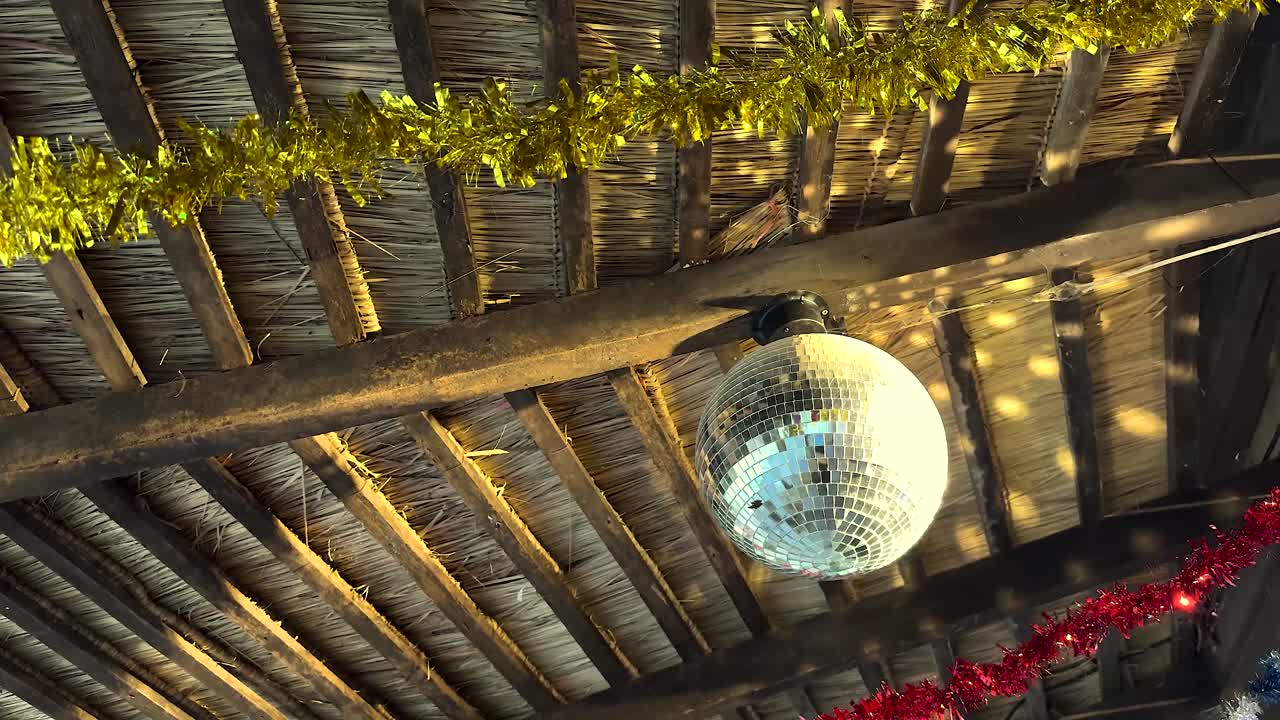 techo de paja rústico con bola de discoteca y decoraciones de navidad