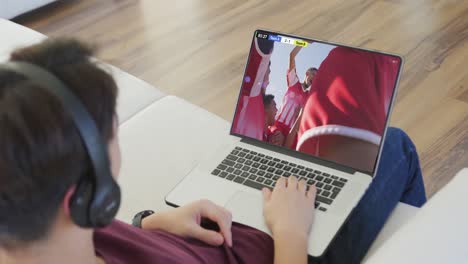 video de una persona sentada en el sofá y viendo un partido de fútbol en una computadora portátil