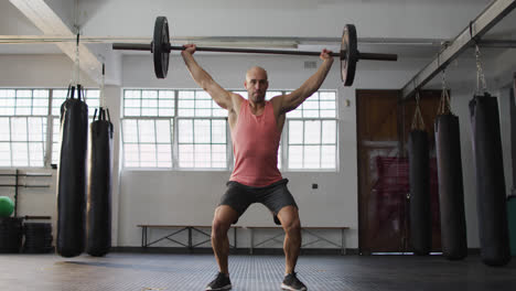 Caucasian-male-trainer-working-out-with-barbell-at-the-gym