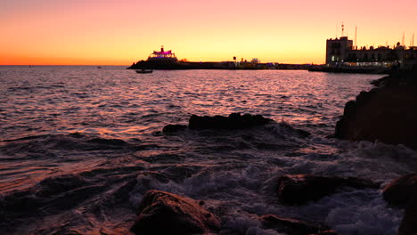 sea waves hitting the reef and rocks and water jumps on stones during sunset orange color looking out at the edge of grand canary island 4k slow motion capture at 60fps.
