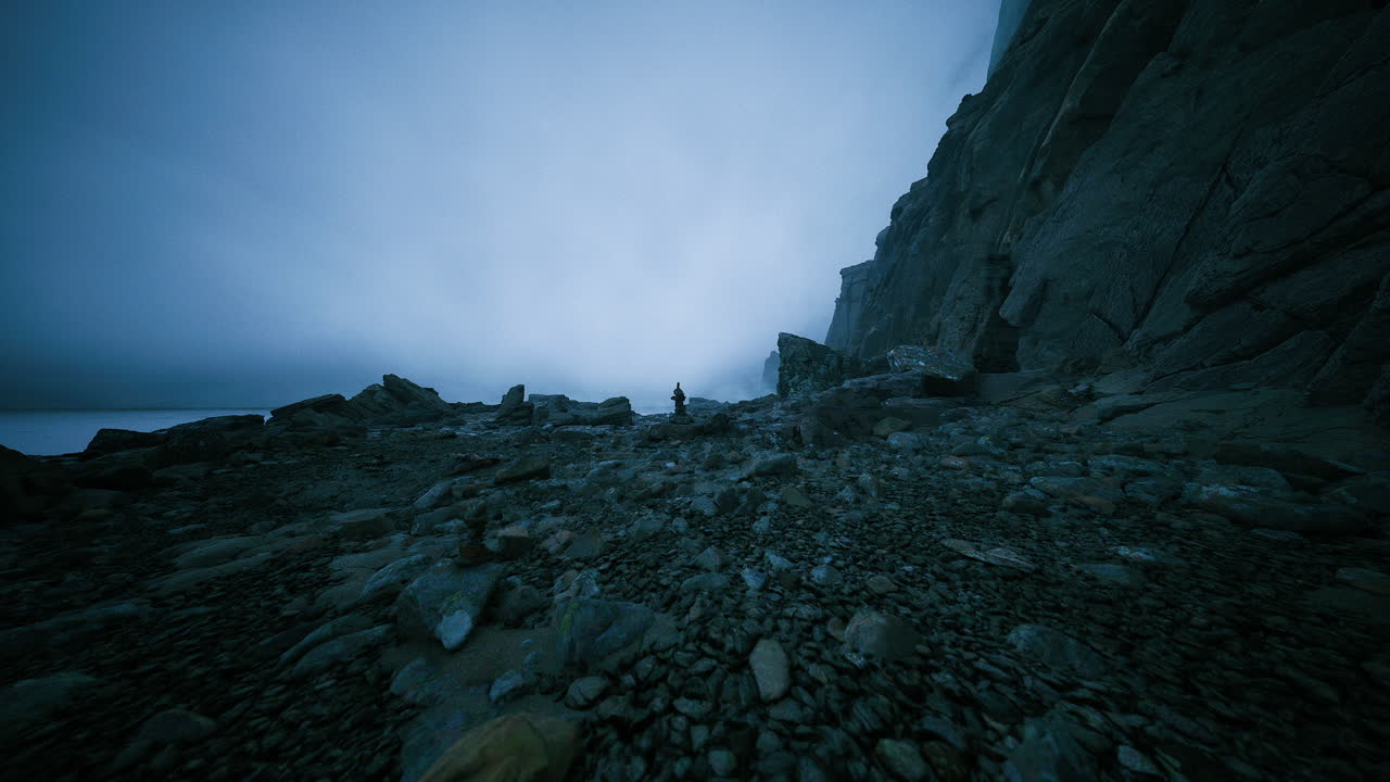 Mysterious figure exploring rugged coastline under foggy twilight sky