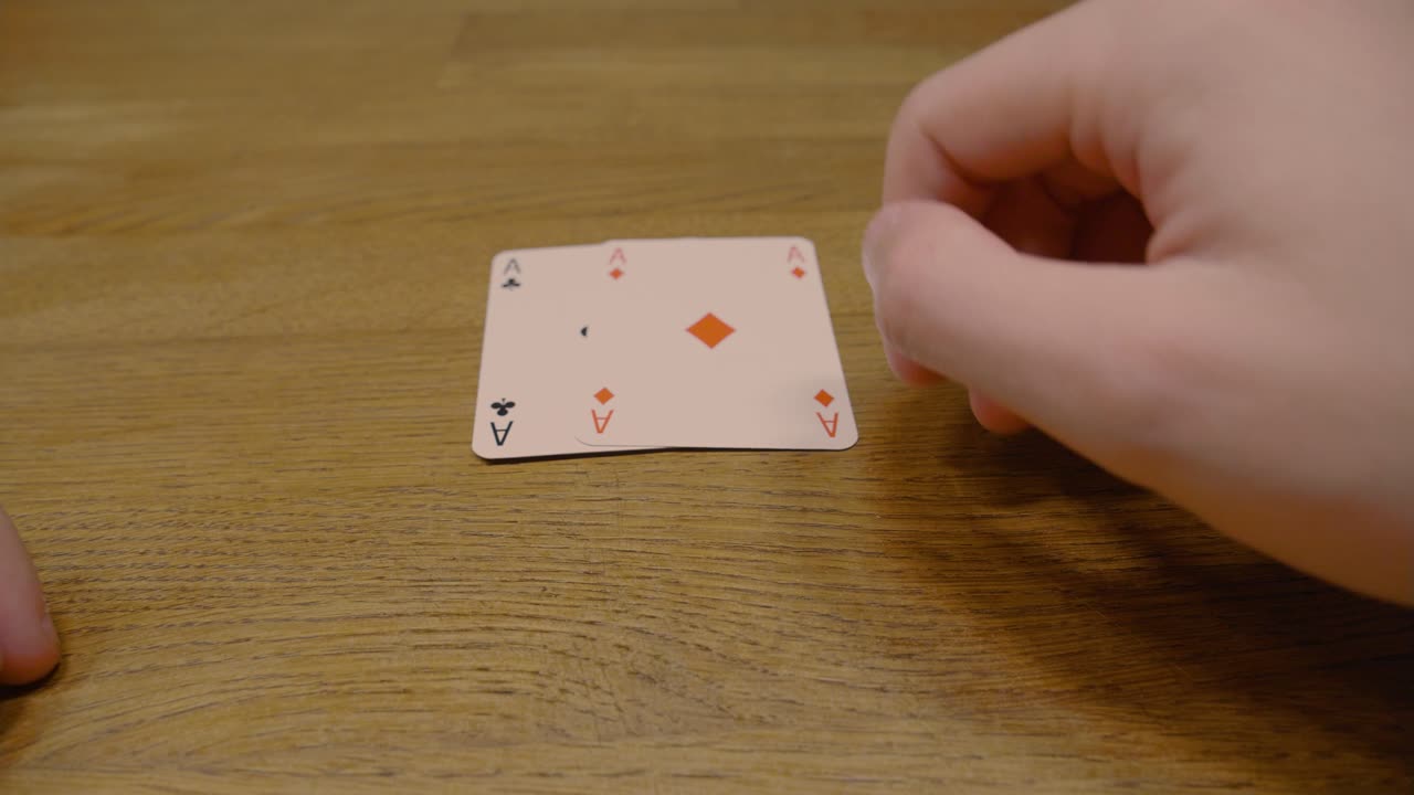 Panning shot of a poker player holding two ace of spades cards during a Texas hold em game on a high quality wooden table