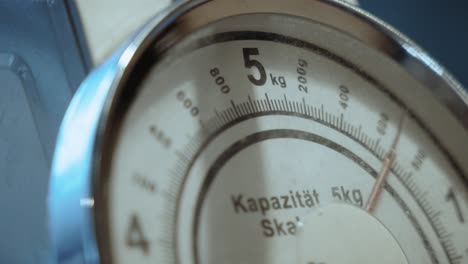 detailed view of a vintage weighing scale set to 5kg, symbolizing precision and measurement. the dominant white color highlights the intricate design.