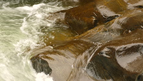 agua que fluye sobre rocas marrones lisas