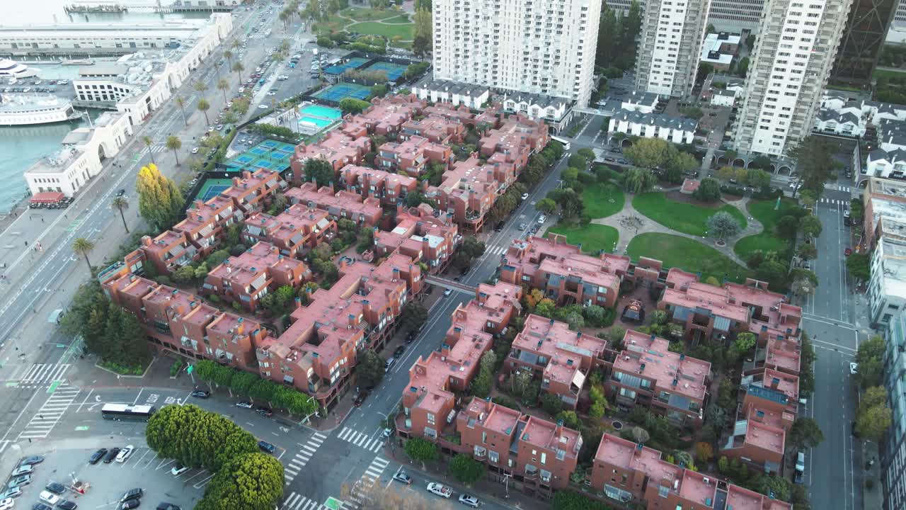vista aérea de una zona residencial con filas de casas adosadas, rodeadas de edificios de gran altura y calles, que muestran la vida urbana