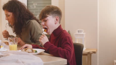 camera focuses a mother and son having dinner at christmas sitting at the table