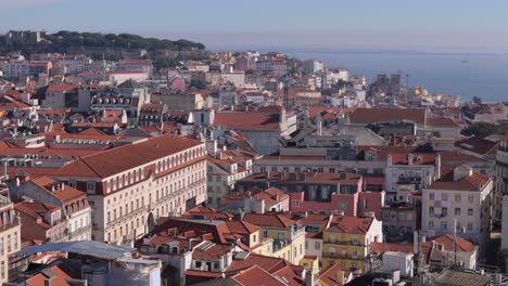 iconic red roofs and beige facades of buildings and homes in lisbon portugal by tagus river