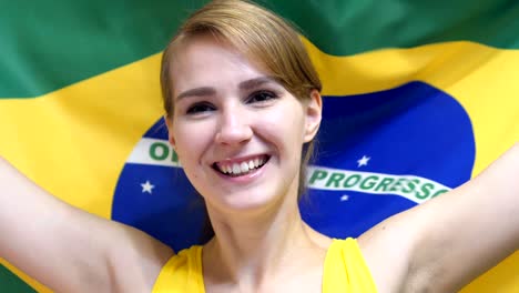 brazilian young woman celebrating while holding the flag of brazil in slow motion