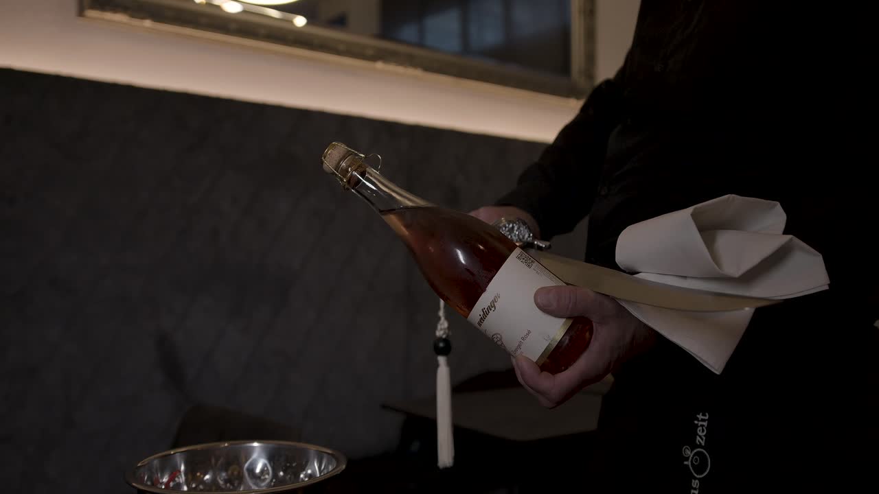 Cameriere che apre una bottiglia di champagne rosé con una sciabola