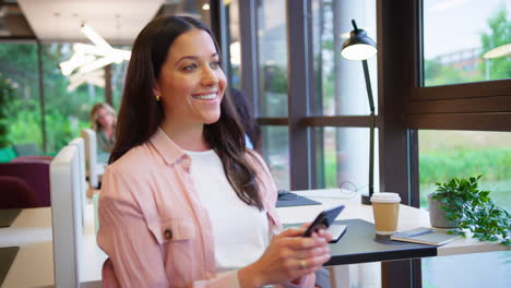 Businesswoman-Sitting-Taking-A-Break-At-Desk-In-Office-Texting-Or-Browsing-On-Mobile-Phone