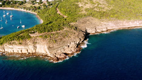 toma aérea soleada del puerto inglés en antigua, caribe con vistas de yates, veleros, puerto deportivo, bahía y acantilados