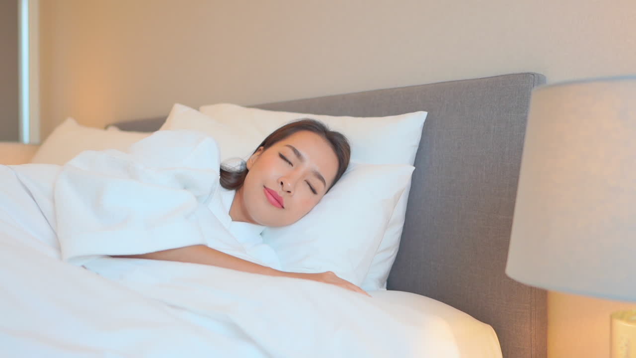 호텔 침실의 편안한 침대에서 잘 자고 있는 아름다운 젊은 아시아 여성