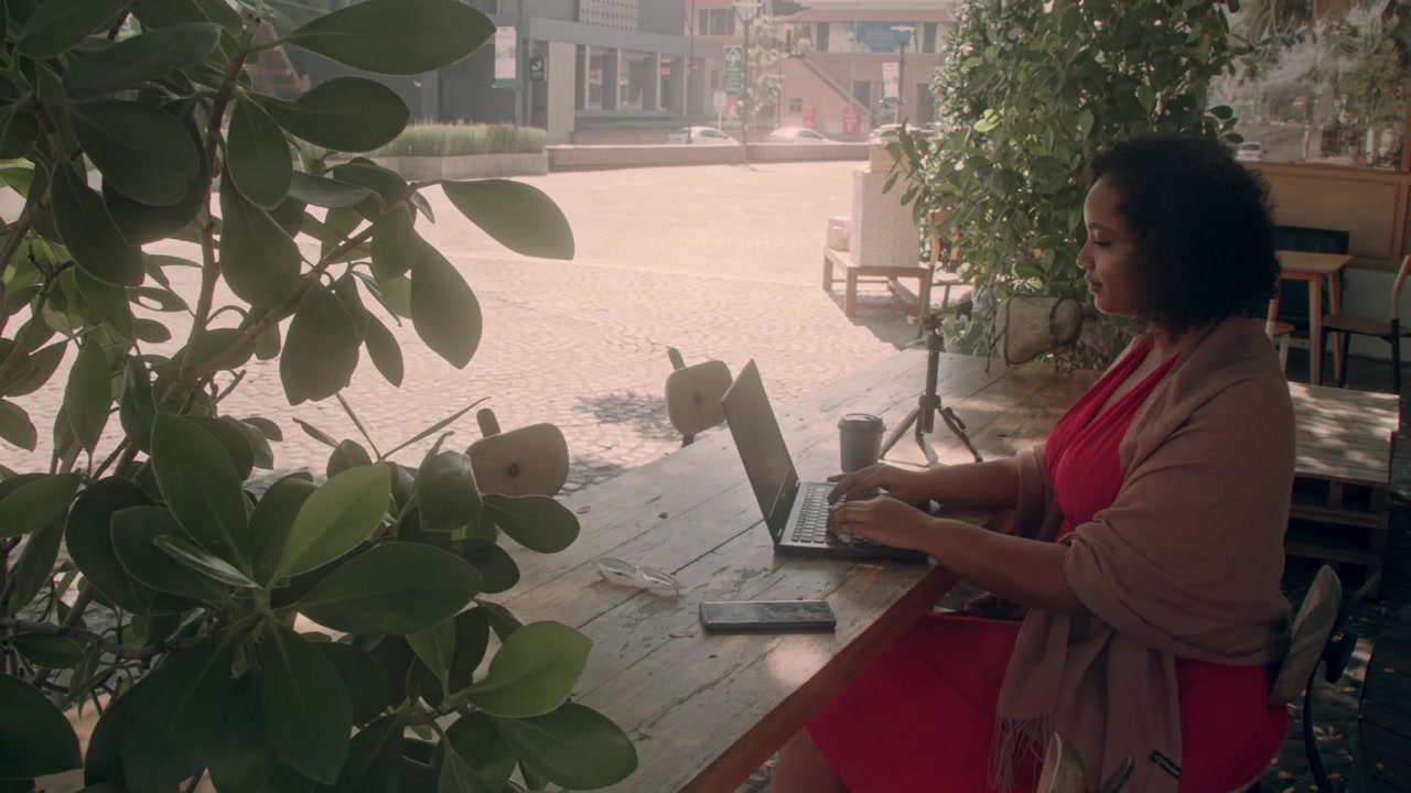 Mulher trabalhando em laptop em uma mesa de café ao ar livre