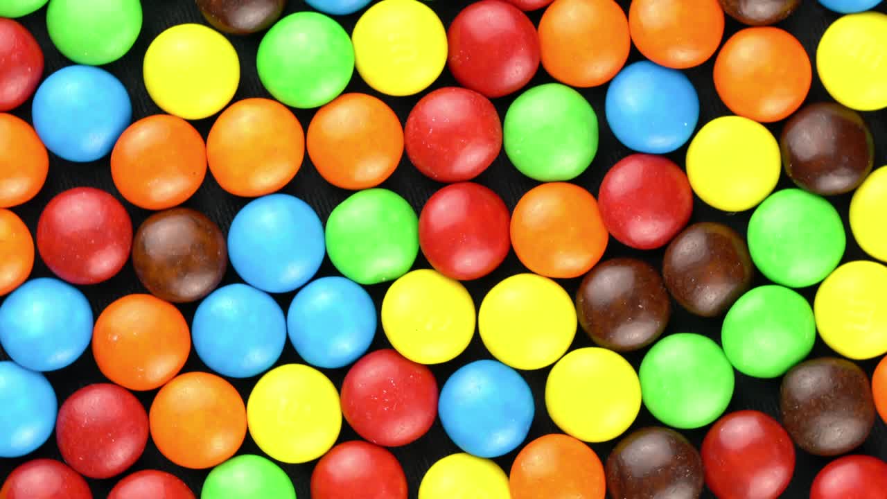 vista superior del surtido de frijoles de caramelo multicolores que giran sobre un fondo negro.