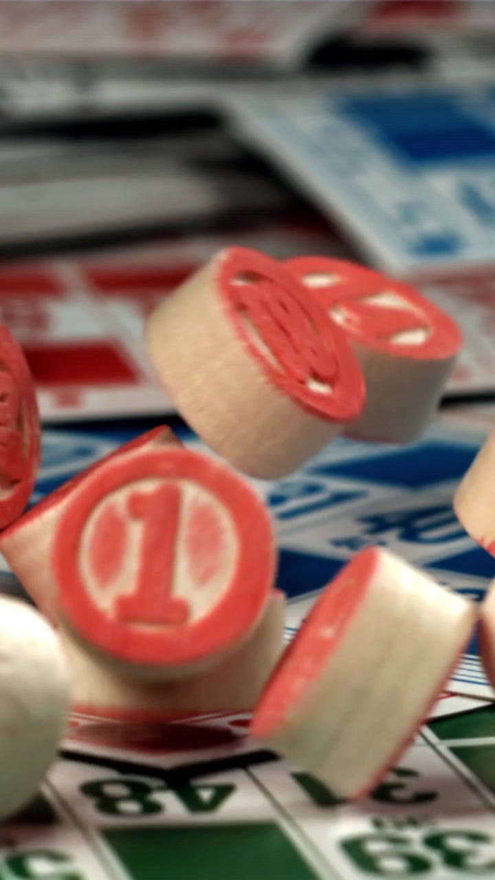 Numeri del bingo in legno che cadono su cartelle da gioco colorate