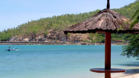 vista panorámica de una mesa de picnic con techo de paja en la playa con océano turquesa en dili, timor-leste, sudeste asiático
