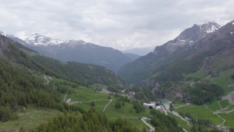 Italian-Alpine-valley-green-forest-meadows-idyllic-hiking-scenery-AERIAL