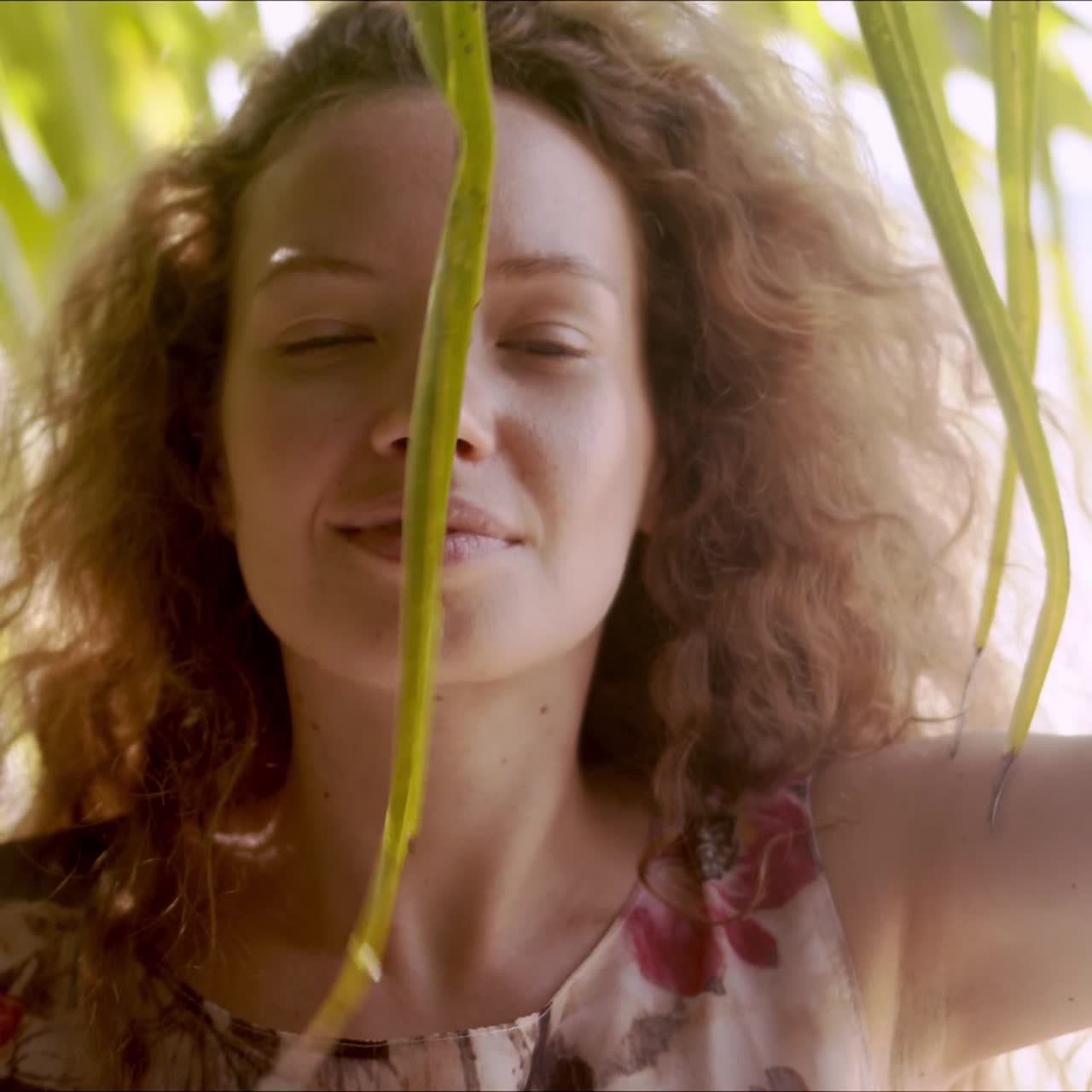 mujer relajada de pie detrás de hojas de palma