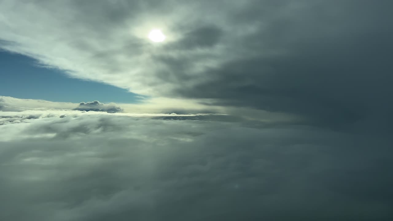 Immersive pilot’s eye view taken from a jet cockpit while flying through leyers of threatening clouds near a massive storm cloud, with the sun veiled. handheld camera 4K shot