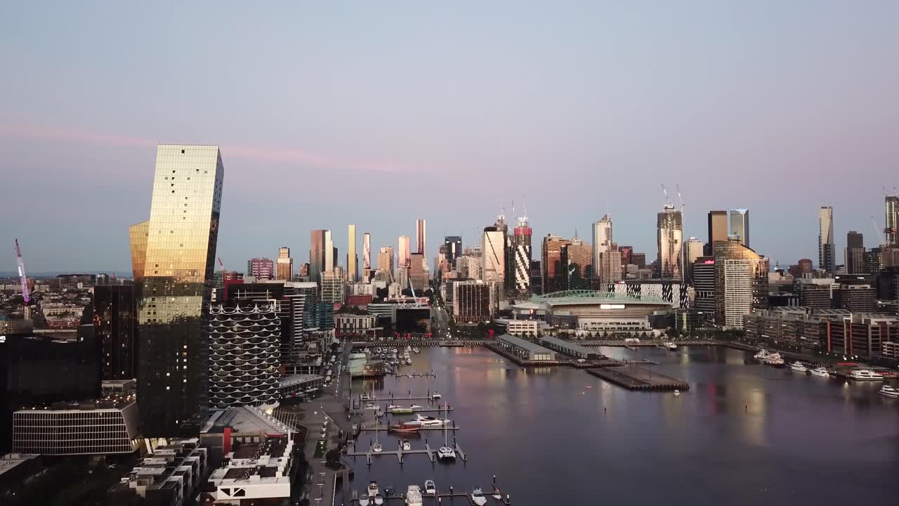 Drone Fly toward Melbourne City over Docklands River Victoria Harbour in sunset