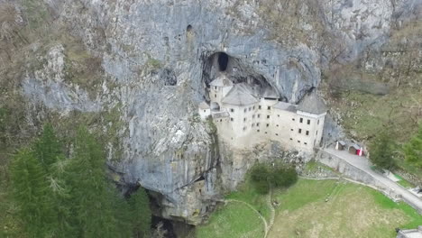 drone shot of mysterious predjama castle, built in a cave mouth in the mountains of slovenia