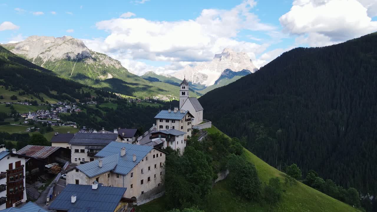 Aerial view, Santa Lucia church nestled in lush Dolomite mountain valley, Italy