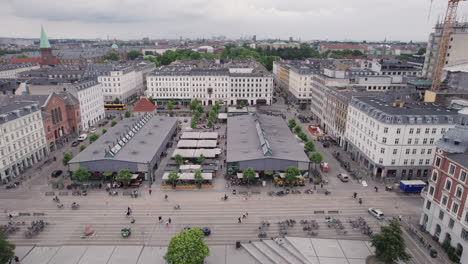 Overflying-Torvehallerne-in-the-middle-of-the-day,-amidst-people-and-cars,-in-the-heart-of-Copenhagen