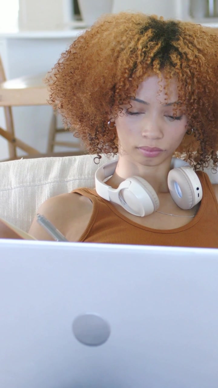 Vertical video: Glancing at offscreen cue woman rust top using stylus working laptop tablet at home